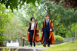 2 students in orange robes walking
