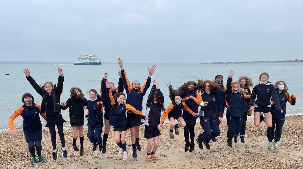 students jumping for joy by the beach