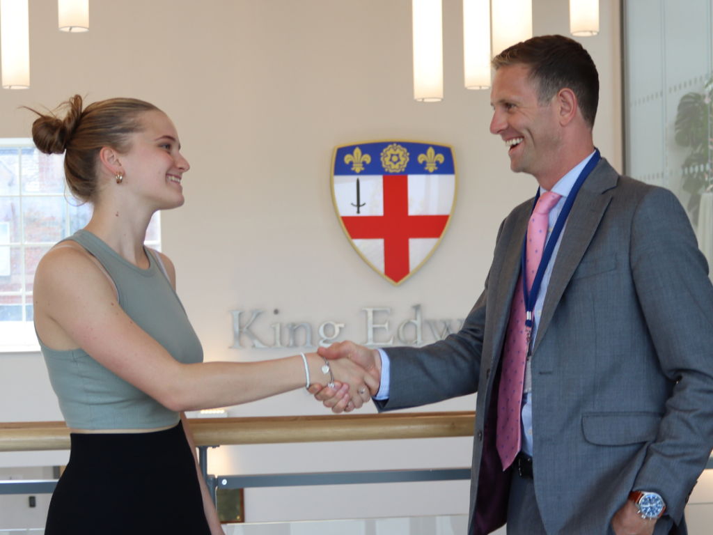 student shaking hands with a man