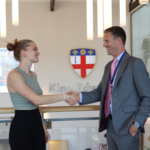 student shaking hands with a man